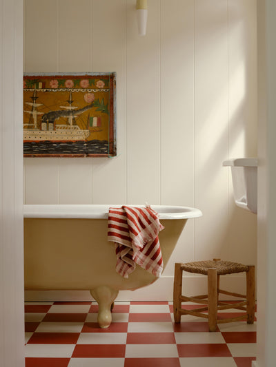 Bathroom with a freestanding bathtub, checkered floor, and decorative wall art.