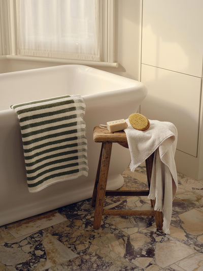 Bathroom scene with a bathtub, wooden stool, and towels.