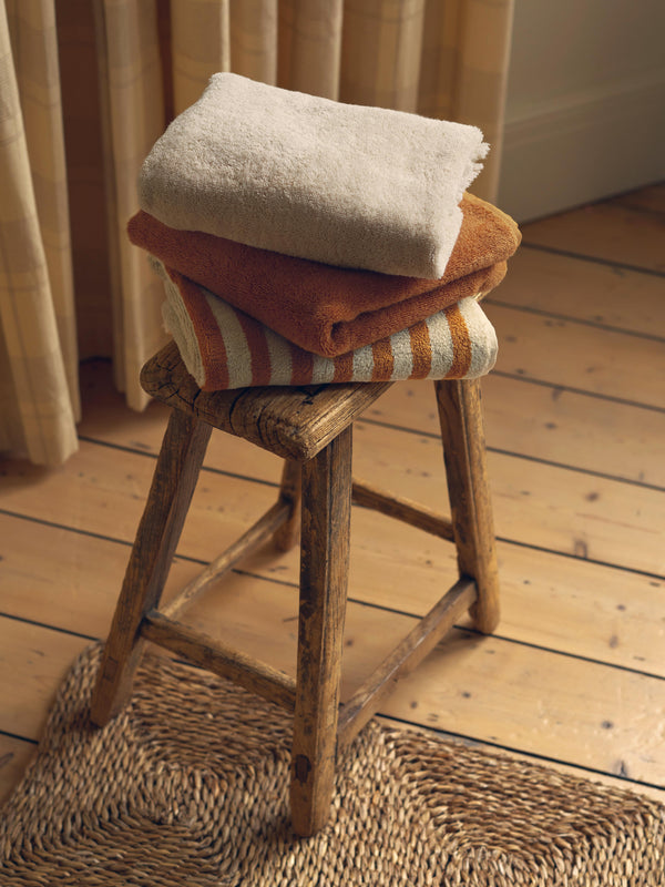 Stack of folded towels on a wooden stool in a home setting