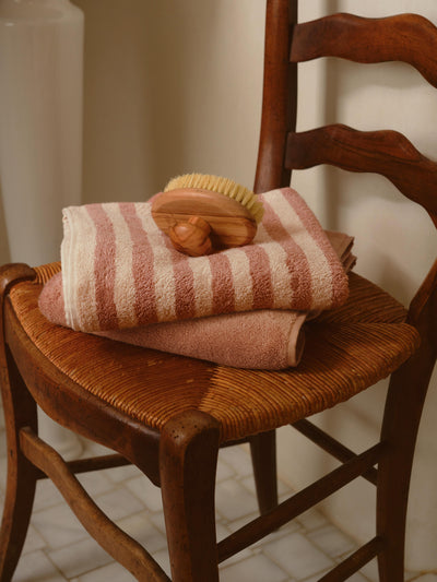 Stack of striped towels with a wooden brush on a wooden chair