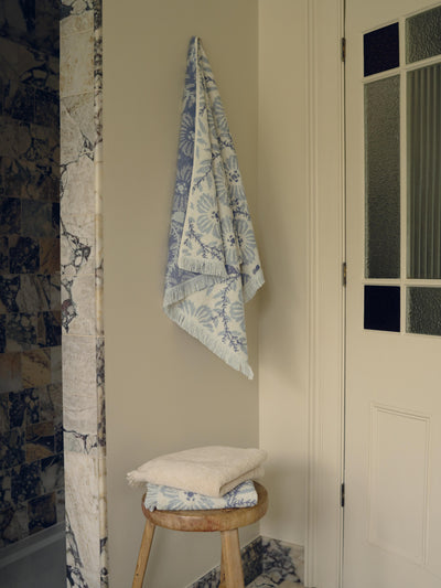 Towel with blue floral pattern hanging on a wall next to a white door.