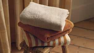 Stack of folded towels on a wooden stool in a home setting