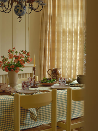 Dining room with a table set for a meal, checkered tablecloth, and floral arrangement.